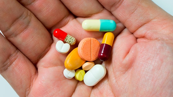 Verschieden farbige Tabletten liegen auf einer Handfläche | Bild: mauritius images / Kenishirotie / Alamy / Alamy Stock Photos
