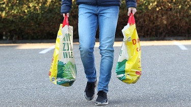 Mann trägt seine Einkäufe in Plastiktüten. Diese sind ab Januar 2022 in Deutschland verboten | Bild: dpa/picture alliance