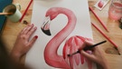 Hände einer Frau malen einen Flamingo auf ein Bild | Bild: mauritius images / Westend61 / Retales Botijero