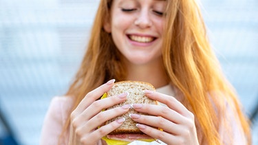 Frau hält Sandwich mit veganer Wurst in den Händen | Bild: mauritius images