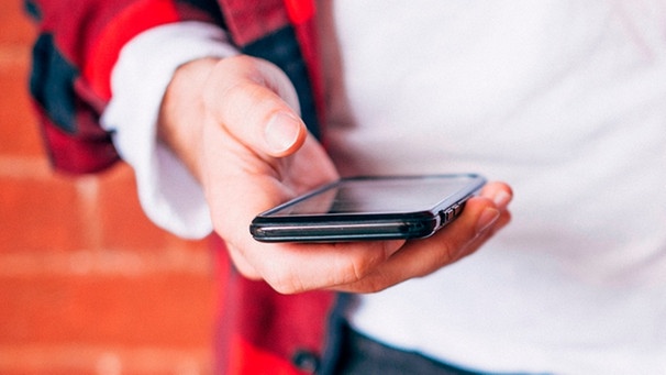 Hand hält ein Smartphone. | Bild: mauritius images