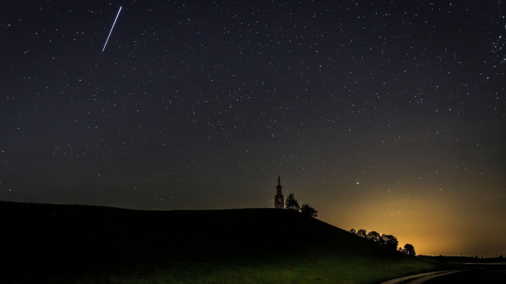 Eine Sternschnuppe fliegt über dem Ridmonument im Allgäu. | Bild: mauritius images