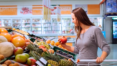 Frau sucht Obst im Supermarkt aus. | Bild: mauritius-images