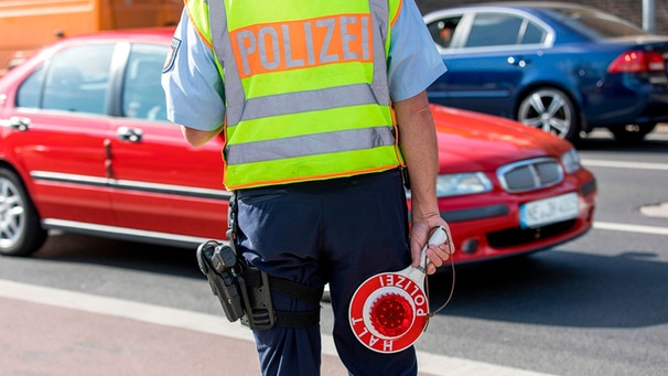 Polizist steht bei einer Verkehrskontrolle am Straßenrand | Bild: mauritius images