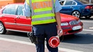 Polizist steht bei einer Verkehrskontrolle am Straßenrand | Bild: mauritius images