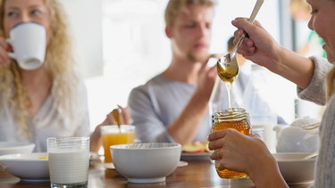 Familie beim Frühstück mit Honigglas | Bild: mauritius