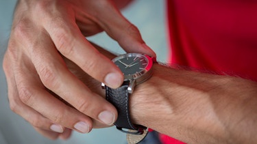 Ein Mann stellt seine Armbanduhr. | Bild: mauritius images / Westend61 / JLPfeifer