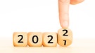 Finger dreht Zahlenwürfel von 2021 auf 2022 um | Bild: mauritius images