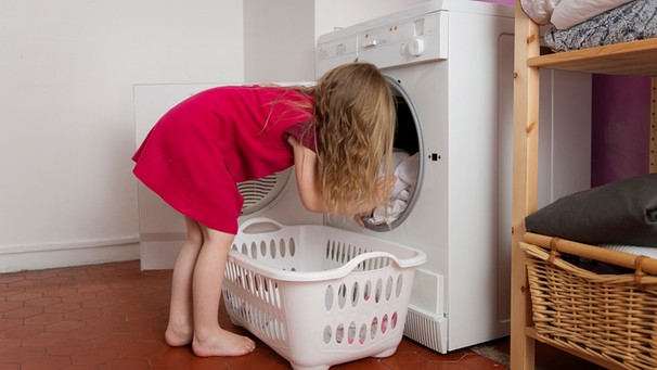 Ein Mädchen räumt die Waschmaschine aus | Bild: mauritius-images