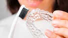 Eine Frau hält eine Zahnbürste und eine Zahnschiene in der Hand | Bild: mauritius images