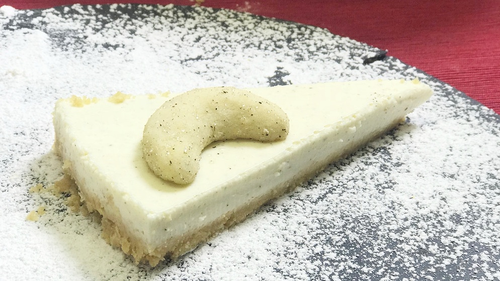 Eine cremiges Stück Torte mit Pannacotta-Füllung, auf dem ein Vanillekipferl drapiert ist. | Bild: BR
