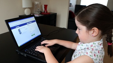 Kleines Mädchen öffnet Facebookseite am Laptop | Bild: picture alliance / empics