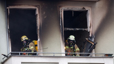 Feuerwehrleute stehen in einer ausgebrannten Wohnung. | Bild: picture-alliance/dpa