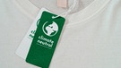 Ein T-Shirt wird beworben mit dem Wort "klimaneutral" | Bild: mauritius images
