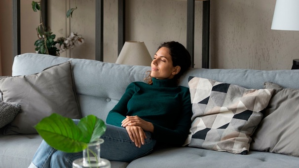 Eine Frau sitzt auf einem Sofa in einem Wohnzimmer | Bild: mauritius images