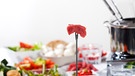 Fonduegabel mit Fleischwürfel vor gedecktem Tisch | Bild: mauritius images