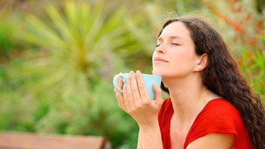 Frau genießt eine Tasse Kaffee im Freien und hat die Augen geschlossen | Bild: mauritius images / Antonio Guillem Fernández / Alamy / Alamy Stock Photos