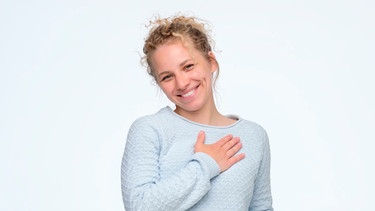 Eine blonde Frau freut sich über ein Kompliment und fasst sich ans Herz | Bild: mauritius images / Victor Koldunov / Alamy / Alamy Stock Photos