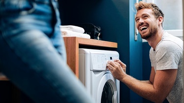 Ein Mann belädt eine Waschmaschine | Bild: mauritius-images