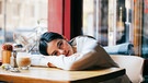 Eine Frau in einem Cafe ist ganz schön müde | Bild: mauritius-images