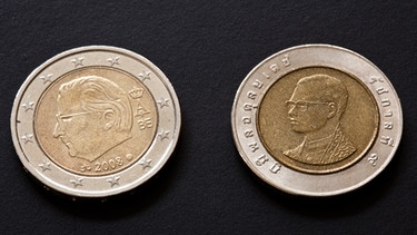 Eine 2-Euro-Münze neben einer 10 Baht Münze | Bild: dpa/picture alliance