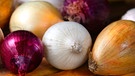 Verschiedene Zwiebelsorten liegen auf einem Tisch | Bild: mauritius images