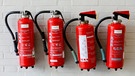 Vier Feuerlöscher hängen an einer Wand | Bild: mauritius images / Rupert Oberhäuser