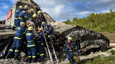 Freiwillige des THW bergen ein Opfer aus den Trümmer eines eingestürzten Hauses. | Bild: BR
