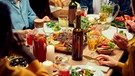 Menschen, von denen man nur die Hände sieht, genießen ein gemeinsames Abendessen mit Braten und Wein | Bild: mauritius images / SeventyFour Images / Alamy / Alamy Stock Photos