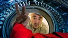Ein Mann blickt in die Waschmaschine | Bild: mauritius images