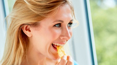 Eine junge Frau isst Chips | Bild: mauritius images / Chris Rout / Alamy / Alamy Stock Photos