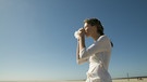 Eine Frau steht am Strand und niest in ein Taschentuch. | Bild: mauritius-images