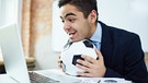 Ein Mann hält einen Fußball in der Hand und guckt in einen Laptop. | Bild: colourbox.com