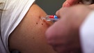 Ein Arzt impft eine Patienten gegen Influenza. | Bild: picture-alliance/dpa