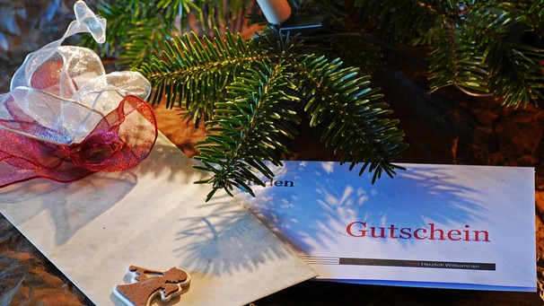 Gutschein-Box liegt unter einem Weihnachtsbaum. | Bild: mauritius images / Tetra Images