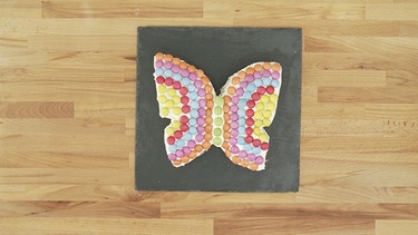 Der fertige Schmetterlingskuchen liegt auf einer Platte. | Bild: BR