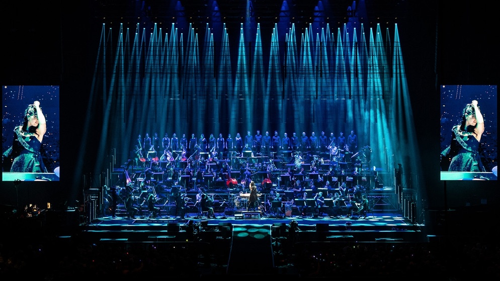 Orchester auf großer Bühne in blaume Rampenlicht | Bild: mTwo.Media