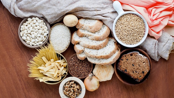 Kohlehydrat -haltige Lebensmittel wie Brot und Nudeln auf einem Holzbrett | Bild: mauritius-images