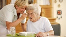 Pflegerin hilft älterer Dame beim Essen | Bild: mauritius-images