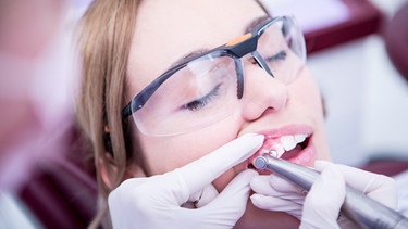 Eine Patientin bei der professionellen Zahnreinigung.  | Bild: mauritius-images