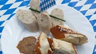 Geschnittene Weißwurst mit Breze und süßem Senf auf einem Teller mit Gabel | Bild: picture-alliance/dpa