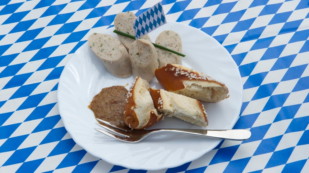 Geschnittene Weißwurst mit Breze und süßem Senf auf einem Teller mit Gabel | Bild: picture-alliance/dpa