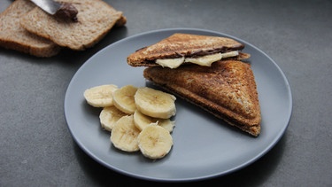 Ein Schoko-Bananen Sandwich liegt auf einem grauen Teller. | Bild: BR
