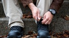 Ein Mann sitzt auf einer Treppe und bindet seine Schuhe. | Bild: picture-alliance/dpa