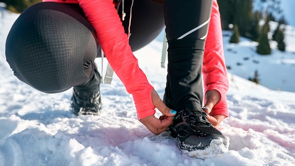 Frau schaut auf ihre Schuhe im Schnee | Bild: mauritius images / Nikita Melnichenko / Alamy / Alamy Stock Photos