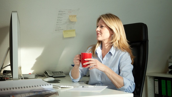 Frau mit Kaffee im Büro | Bild: mauritius-images