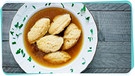 Ein Suppenteller mit Griessnockerln steht auf einem Holztisch | Bild: mauritius images