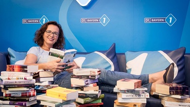 Bayern 1-Moderatorin Ulla Müller liest in einem Stapel voller Bücher | Bild: BR / Philipp Kimmelzwinger