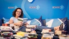 Bayern 1-Moderatorin Ulla Müller liest in einem Stapel voller Bücher | Bild: BR / Philipp Kimmelzwinger