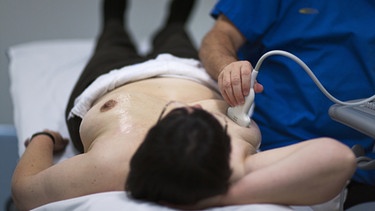 Ein Arzt untersucht die Brust einer Frau mittels Ultraschall. | Bild: picture-alliance/dpa